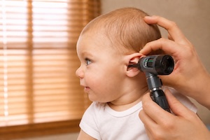 A baby having their ear examined with an otoscope at the clinic.