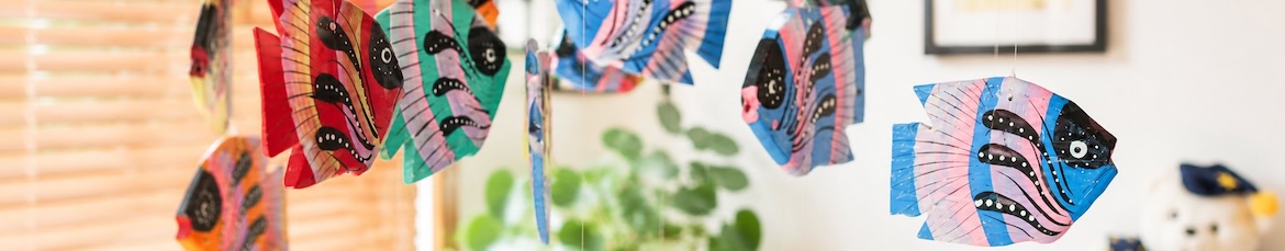 A colourful hand-painted wooden fish mobile hanging in a treatment room.